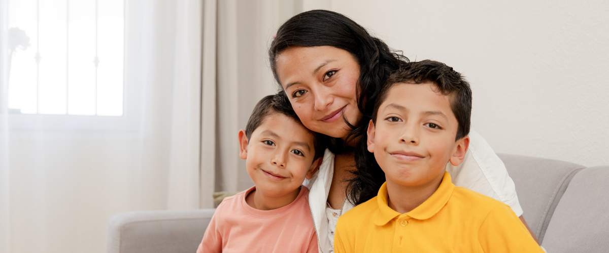 Mother holding children in yellow and salmon colored shirts.